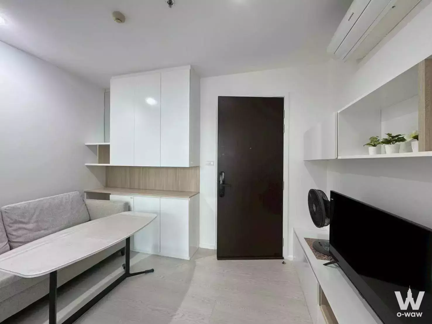 Compact 1-bed condo in The Prodigy MRT Bangkhae with grey sofa, white cabinets, and TV console