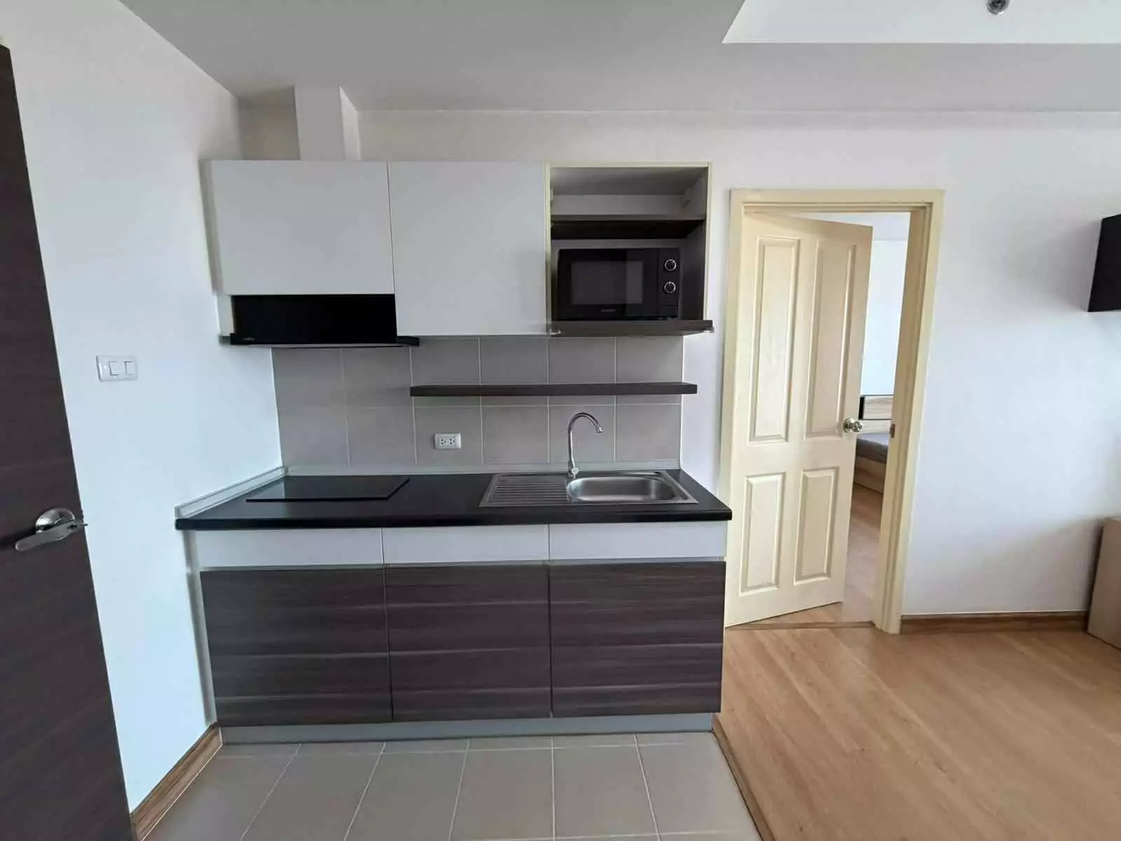 Kitchenette with white cabinets and induction cooktop in 1-bed condo for rent at Supalai Loft Phasi Charoen