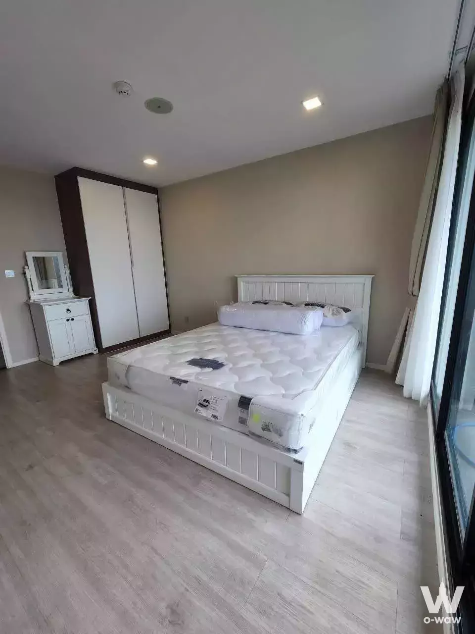 Unfurnished bedroom in Atmoz Ladprao 71 featuring white bed frame, wardrobe, and balcony access
