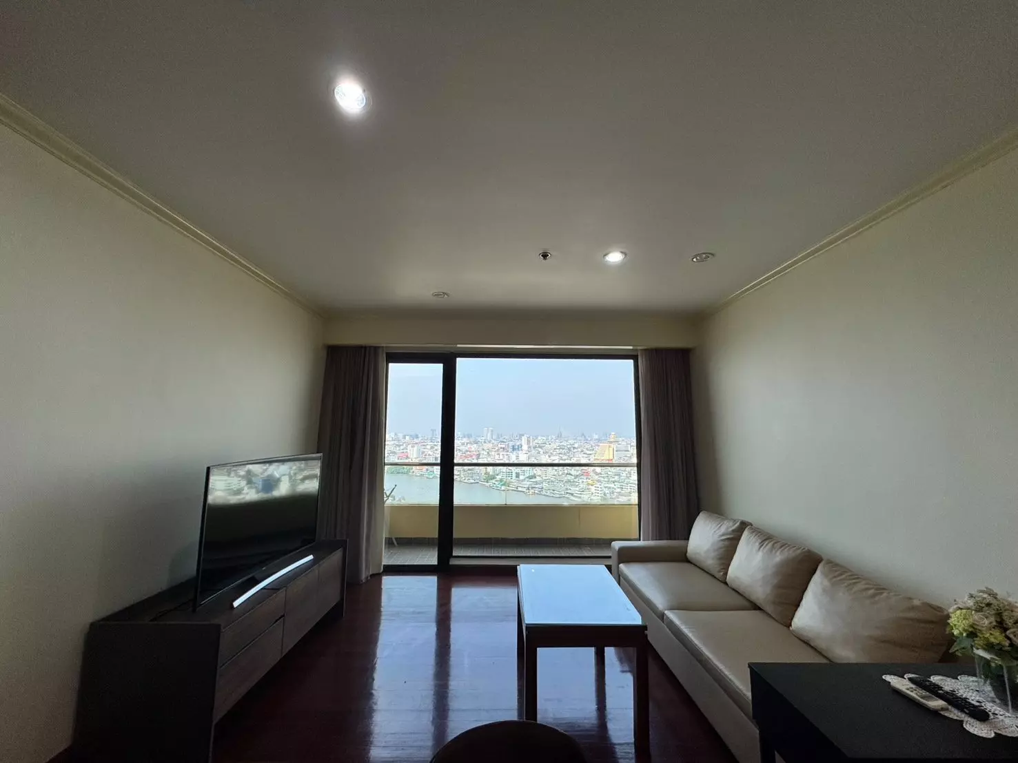 Beige sofa and TV console in living room of 1-bed condo for rent at Baan Chaopraya with river view