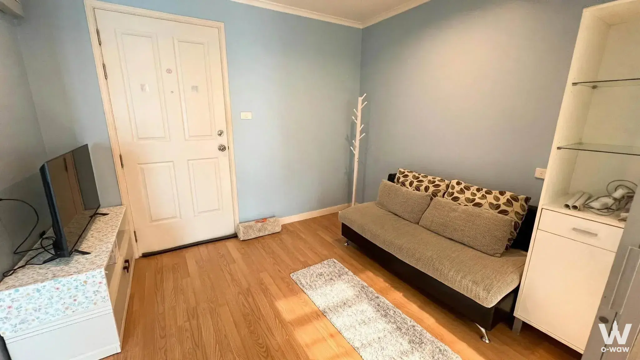 Compact living room in Lumpini Park Pinklao condo with light blue walls and a 2-seater sofa