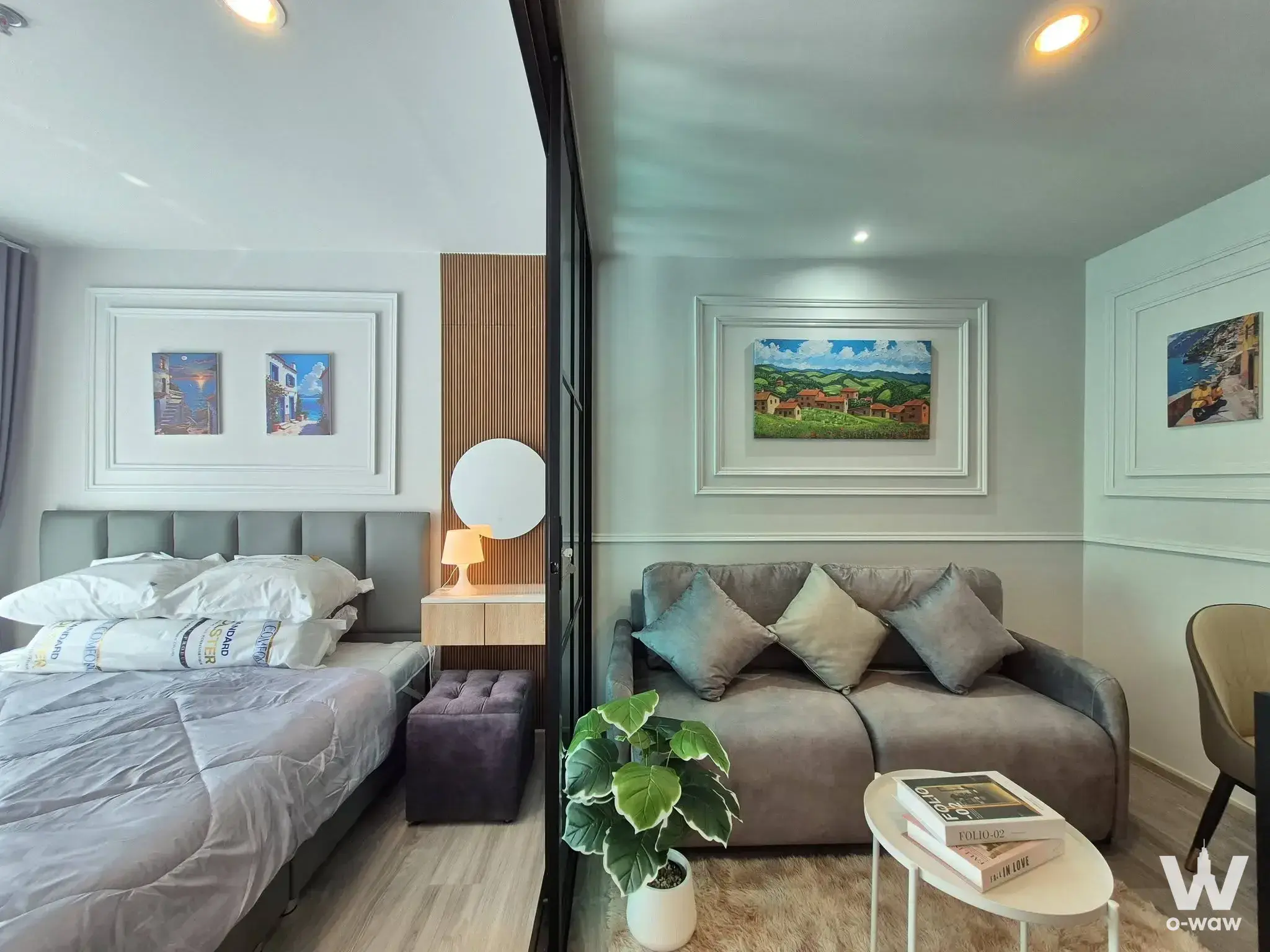Studio in Regent Home Bangna featuring glass partition, bed area, and living space with grey sofa
