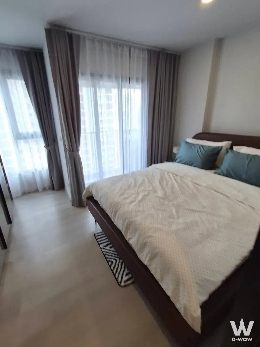 Bedroom in Aspire Onnut Station condo with dark bed frame and teal accents