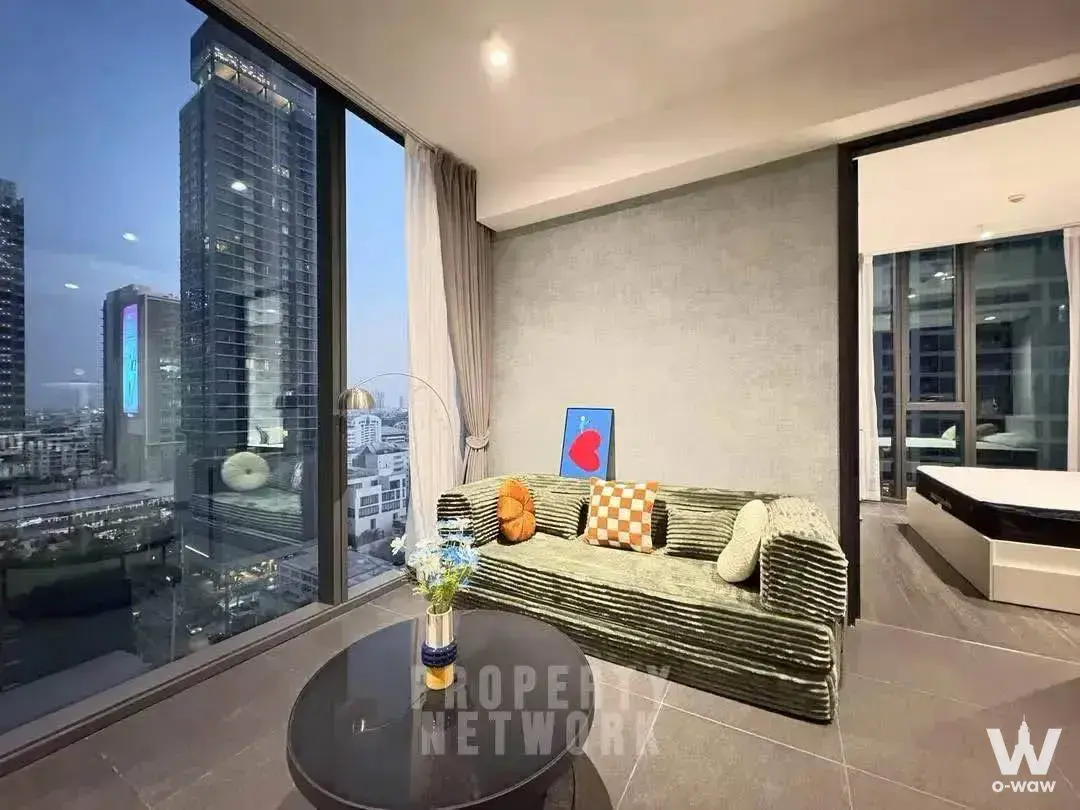 Living room in Tait Sathorn 12 2-bed condo featuring sage-green sofa and city skyline views
