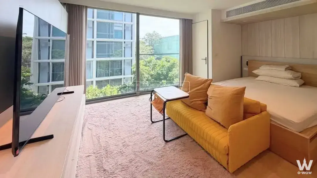 Modern studio bedroom in SCOPE Promsri with yellow sofa, wood flooring, and floor-to-ceiling glass doors