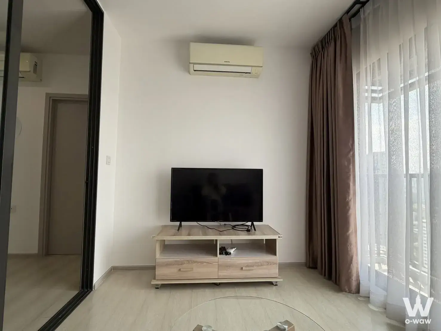 Modern living room in Life Sukhumvit 48 condo with oak TV console and floor-to-ceiling windows