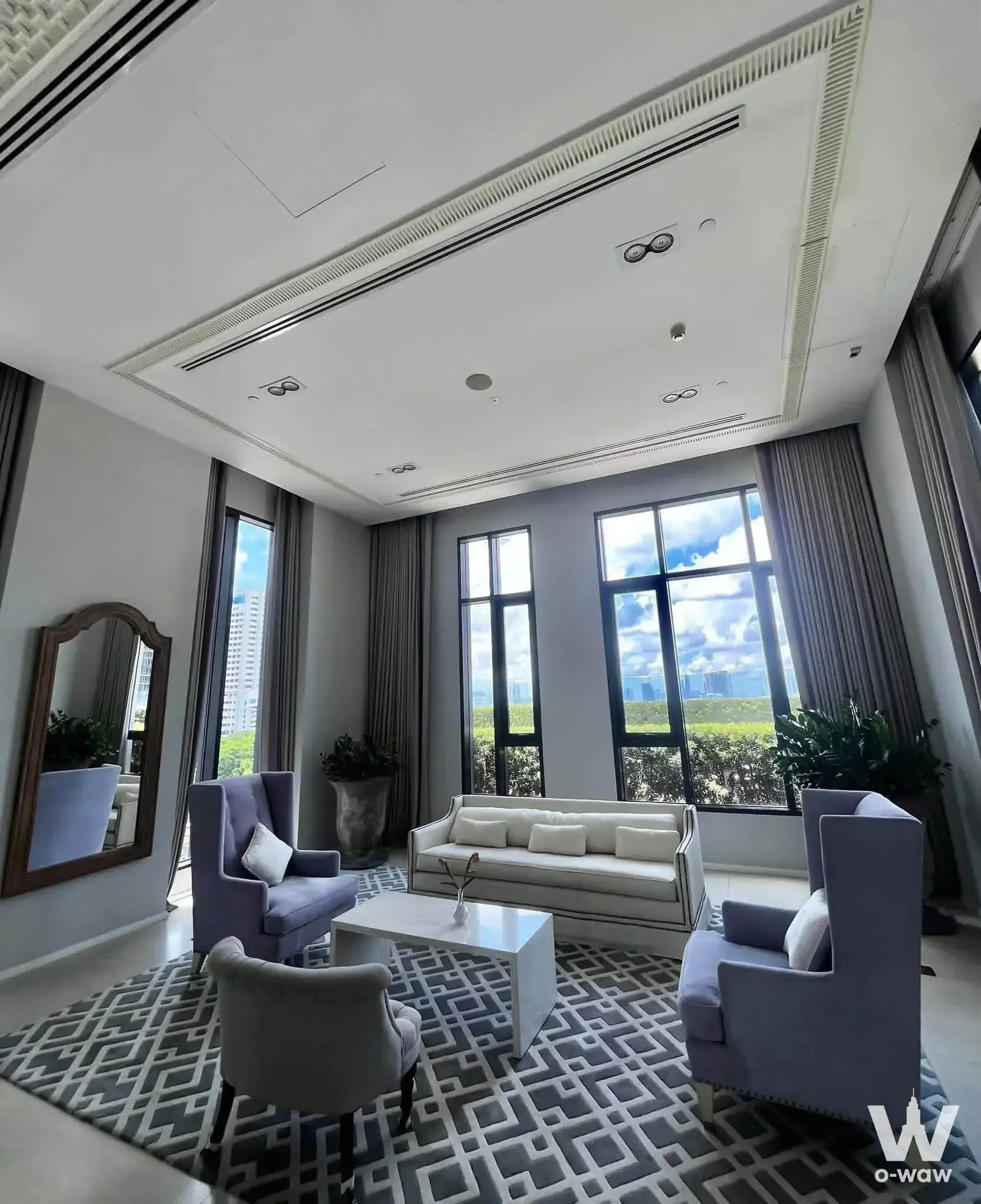 Living room in a 3-bed unit for rent at The Diplomat Sathorn featuring high ceilings, lavender armchairs, and skyline views
