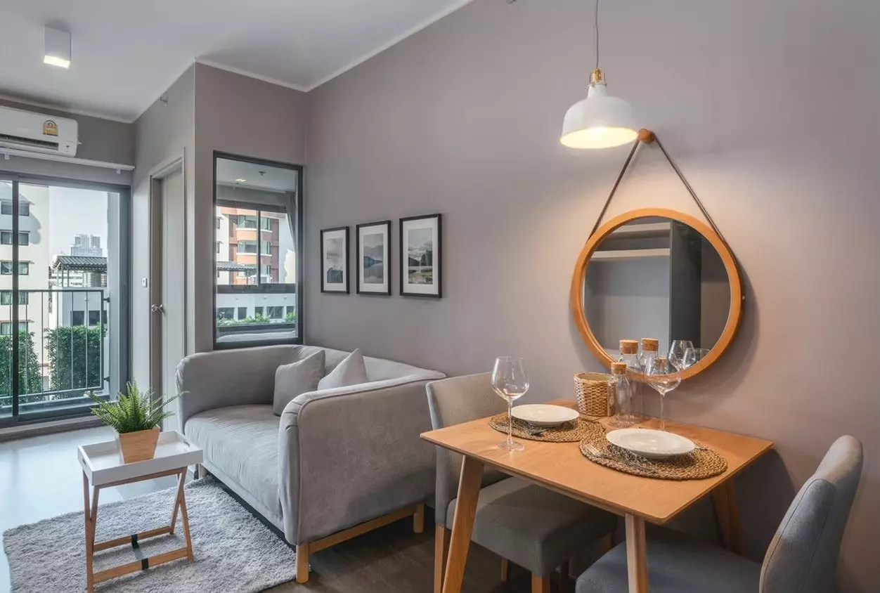 Minimalist living room with grey sofa, dining set, and balcony views in Ideo Sukhumvit 93 condo for rent