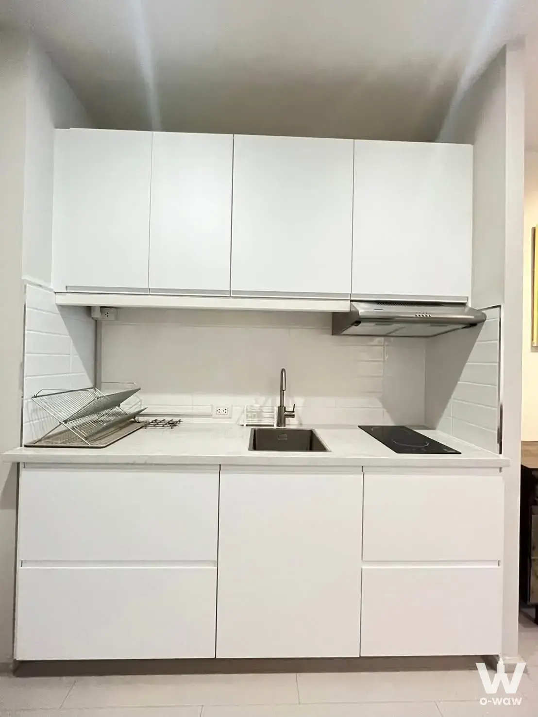 White kitchenette with glossy cabinets, subway tile backsplash, and induction cooktop in Noble Ploenchit condo