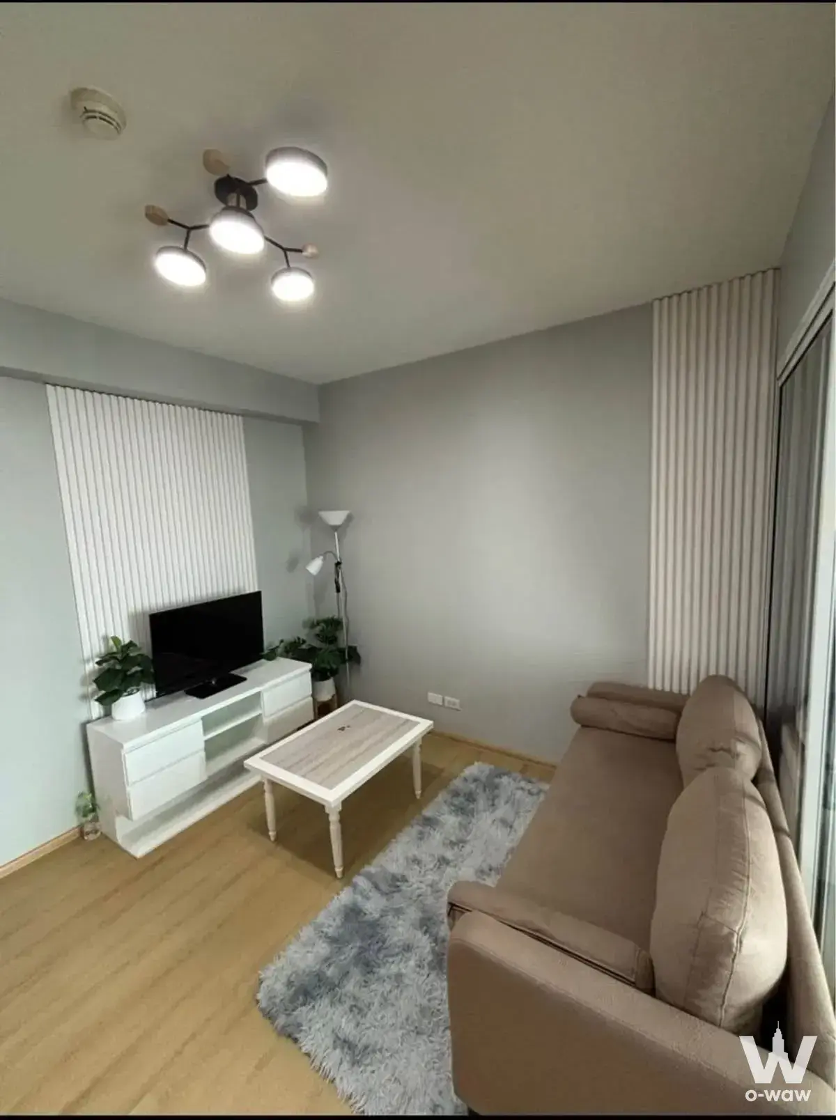 Modern living area in a Fuse Mobius rental with a beige sofa and white floating TV console