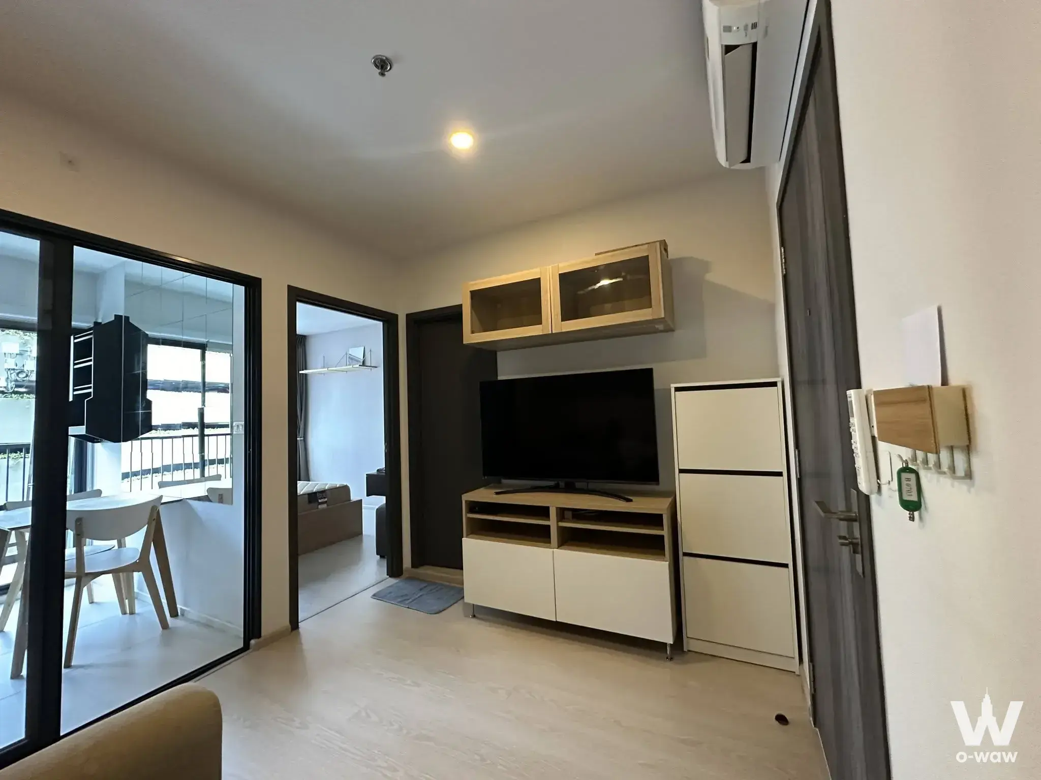 ELIO DEL NEST 1-bed condo living room with sliding glass balcony door and light wood media console