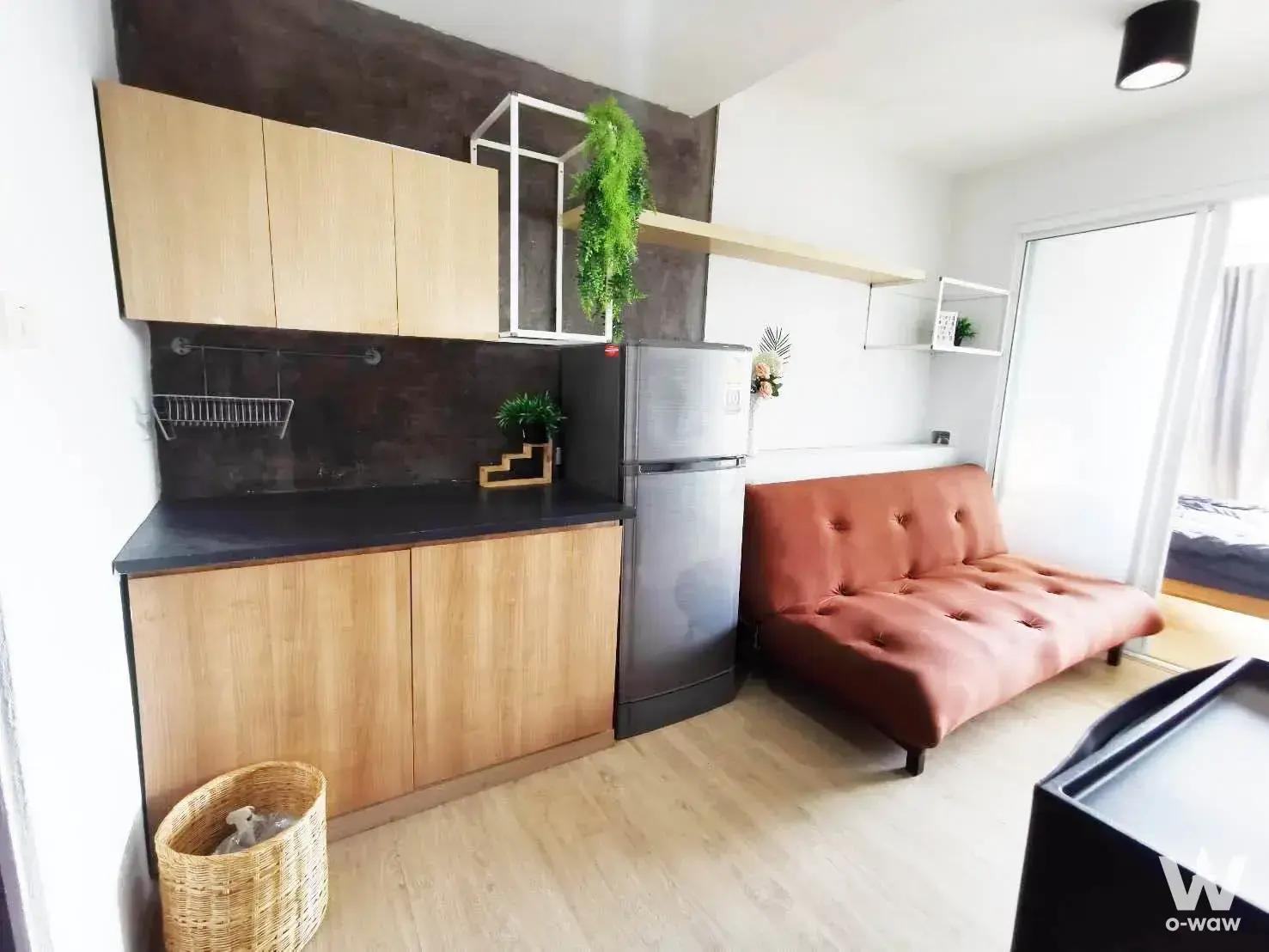 Compact 2-bed condo for sale in Sub Kaew Tower featuring light wood cabinets and a rust-orange sofa bed