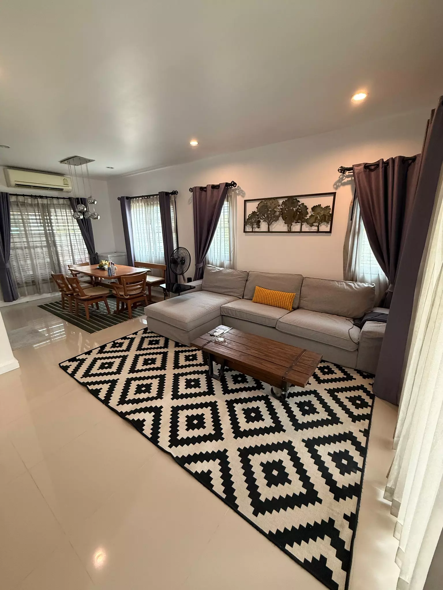 Living room with grey sectional sofa geometric rug and wooden dining set