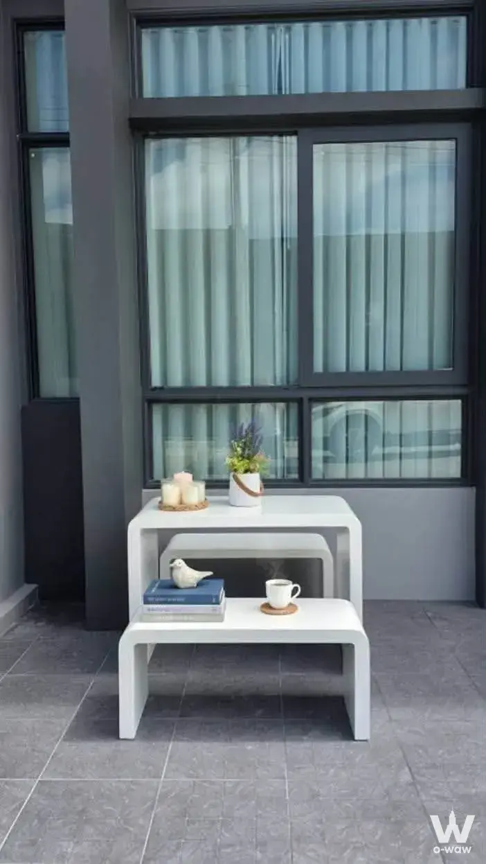 Modern balcony with nested white tables and sheer blue curtains at Siri Place Airport Phuket