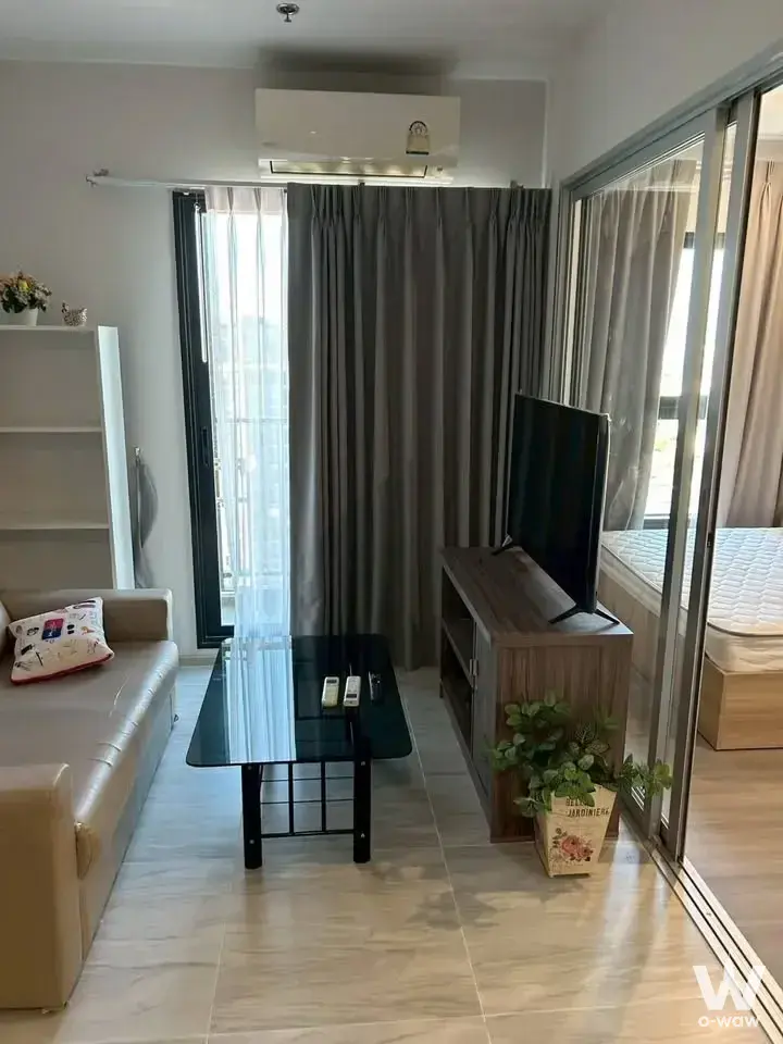 Living room in The Parkland Charan-Pinklao 1-bed condo with beige sofa and balcony access