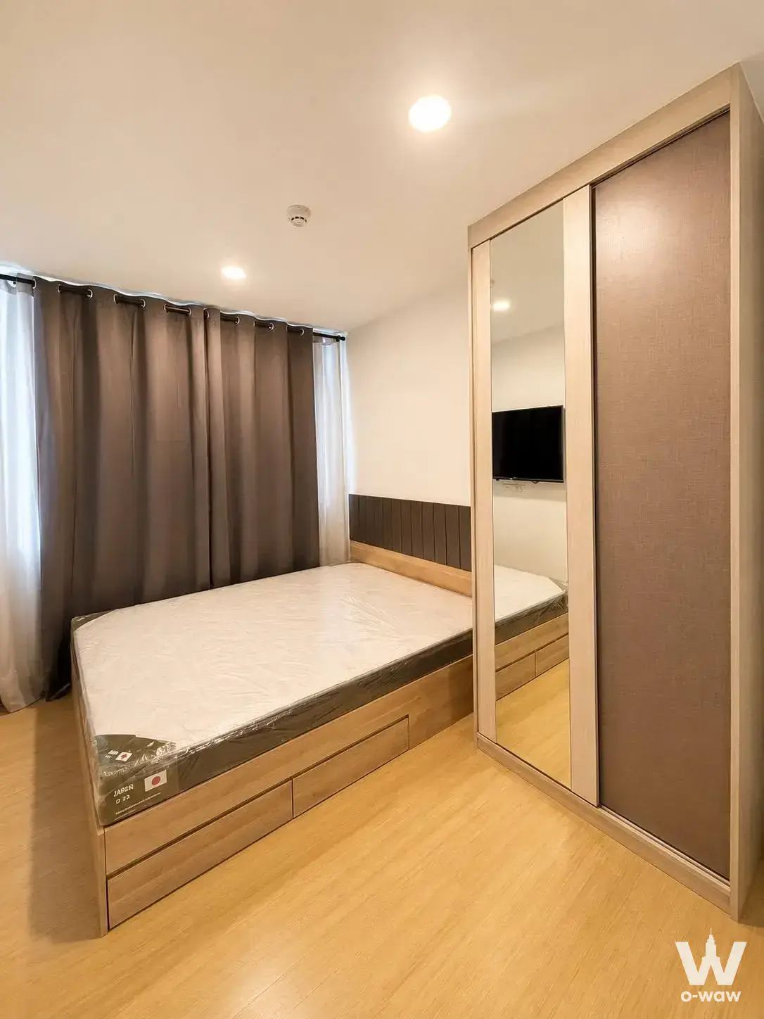 Bedroom in Chewathai Hallmark Ladprao with a light wood platform bed, built-in storage, and mirrored wardrobe