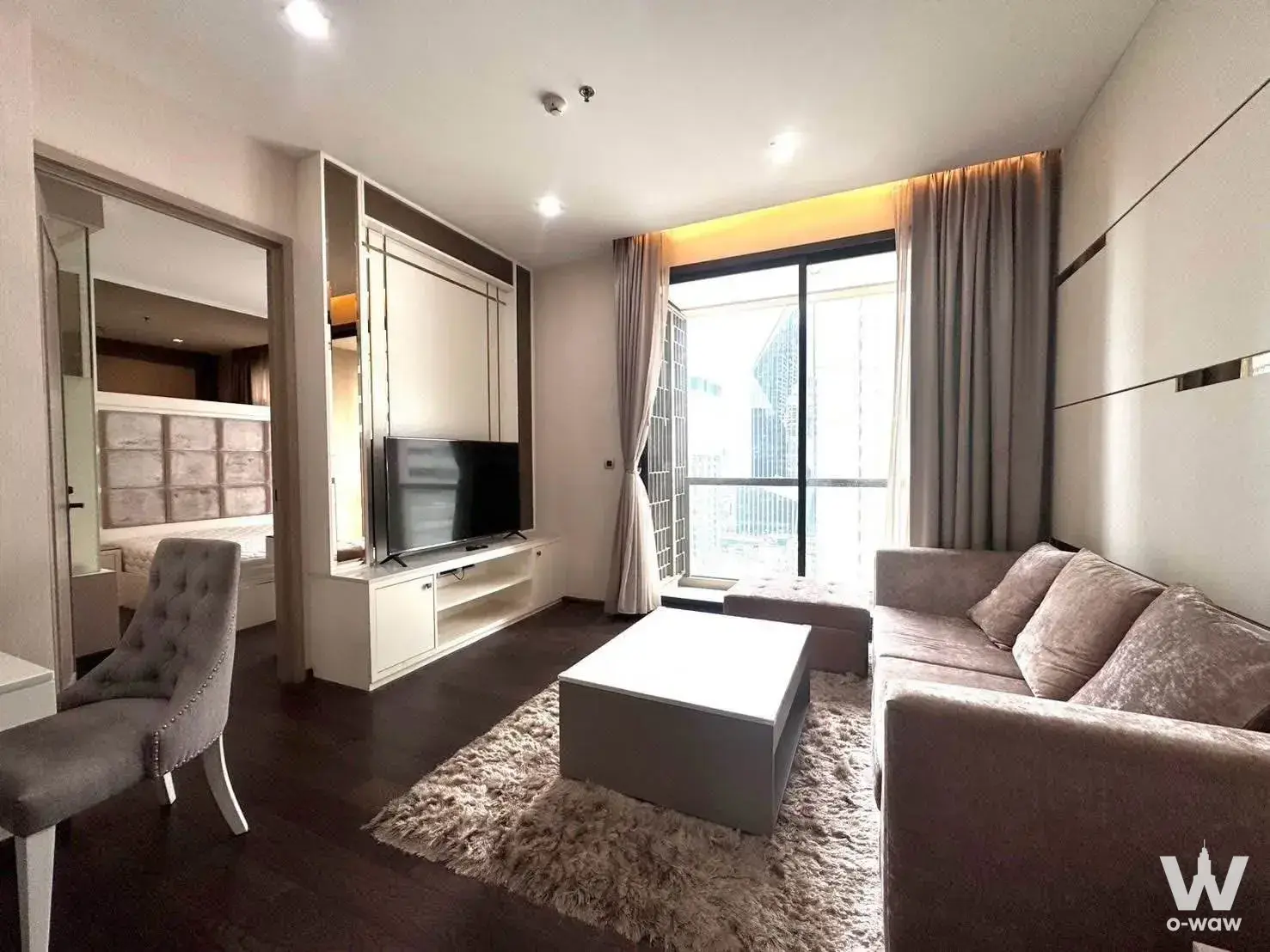 Living room in a THE XXXIX by Sansiri condo with a taupe sofa and floor-to-ceiling city views