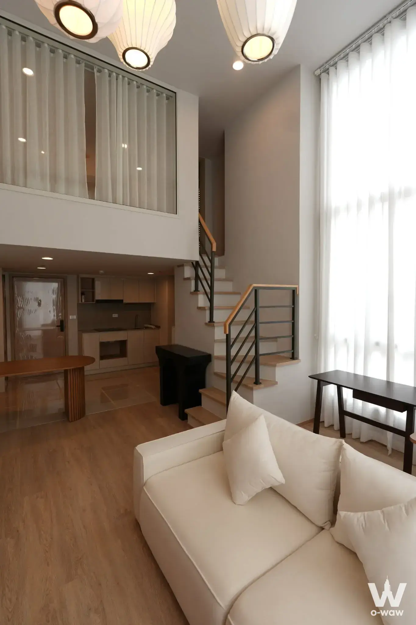 Open-plan duplex living room in Culture Chula with floating staircase and floor-to-ceiling windows