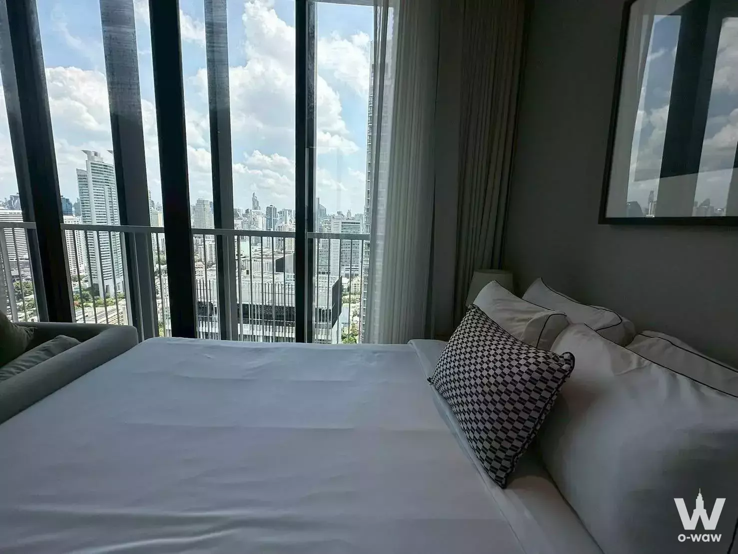 Spacious bedroom in Park Origin Phrom Phong condo with city view, floor-to-ceiling windows, and white linens