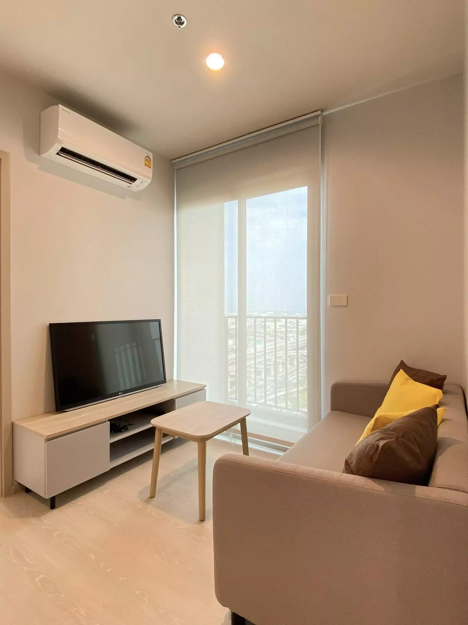 Nue Mega Plus 2-bed condo living room with taupe sofa, media console, and balcony sliding doors