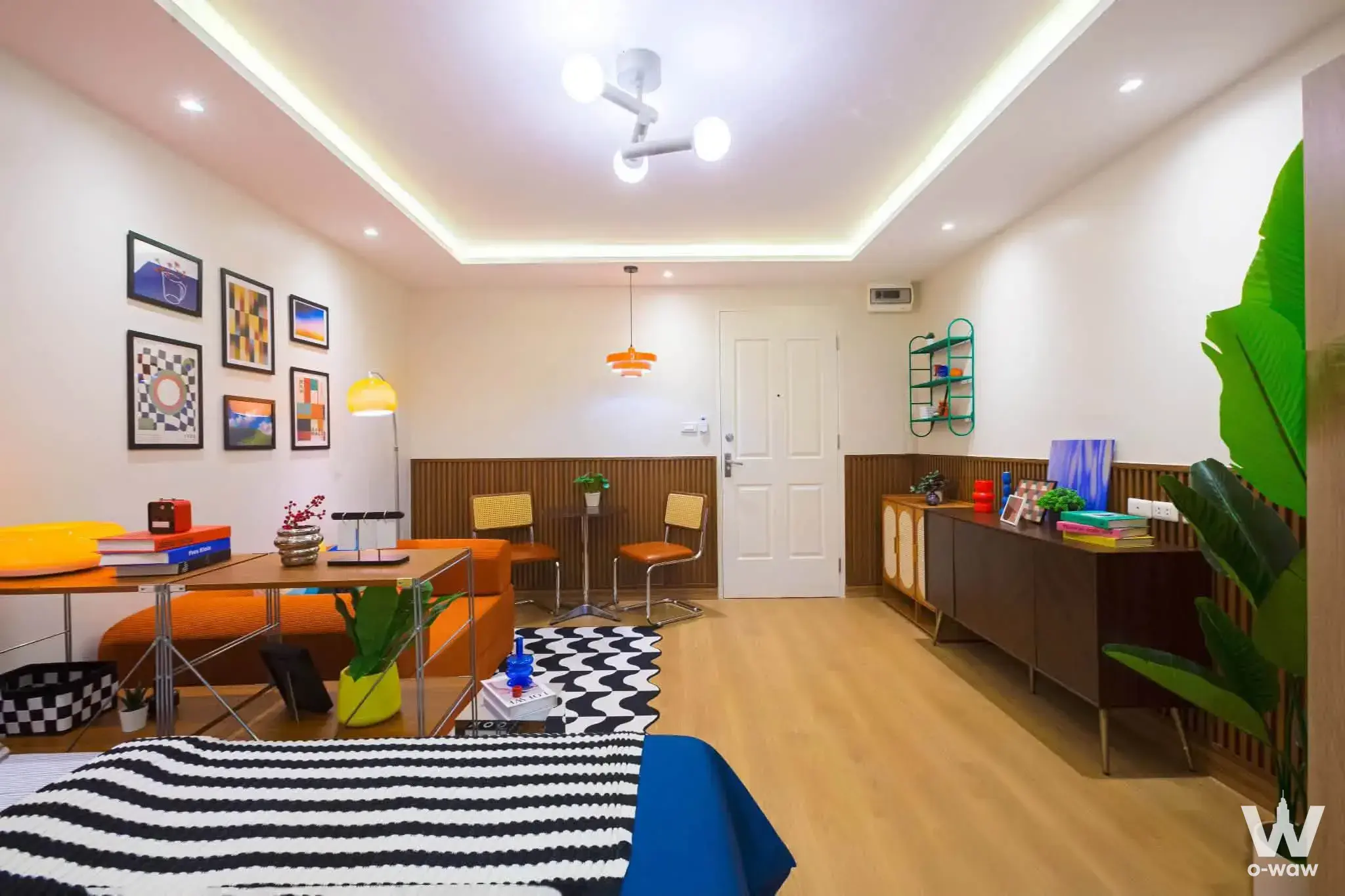 Retro-modern studio in Happy Condo Rachada 18 with orange accents and wood slat wainscoting