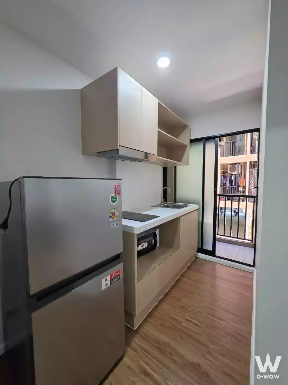Compact kitchenette with stainless steel fridge and cooktop in 1-bed condo for rent at Plum Condo Rangsit Alive 2