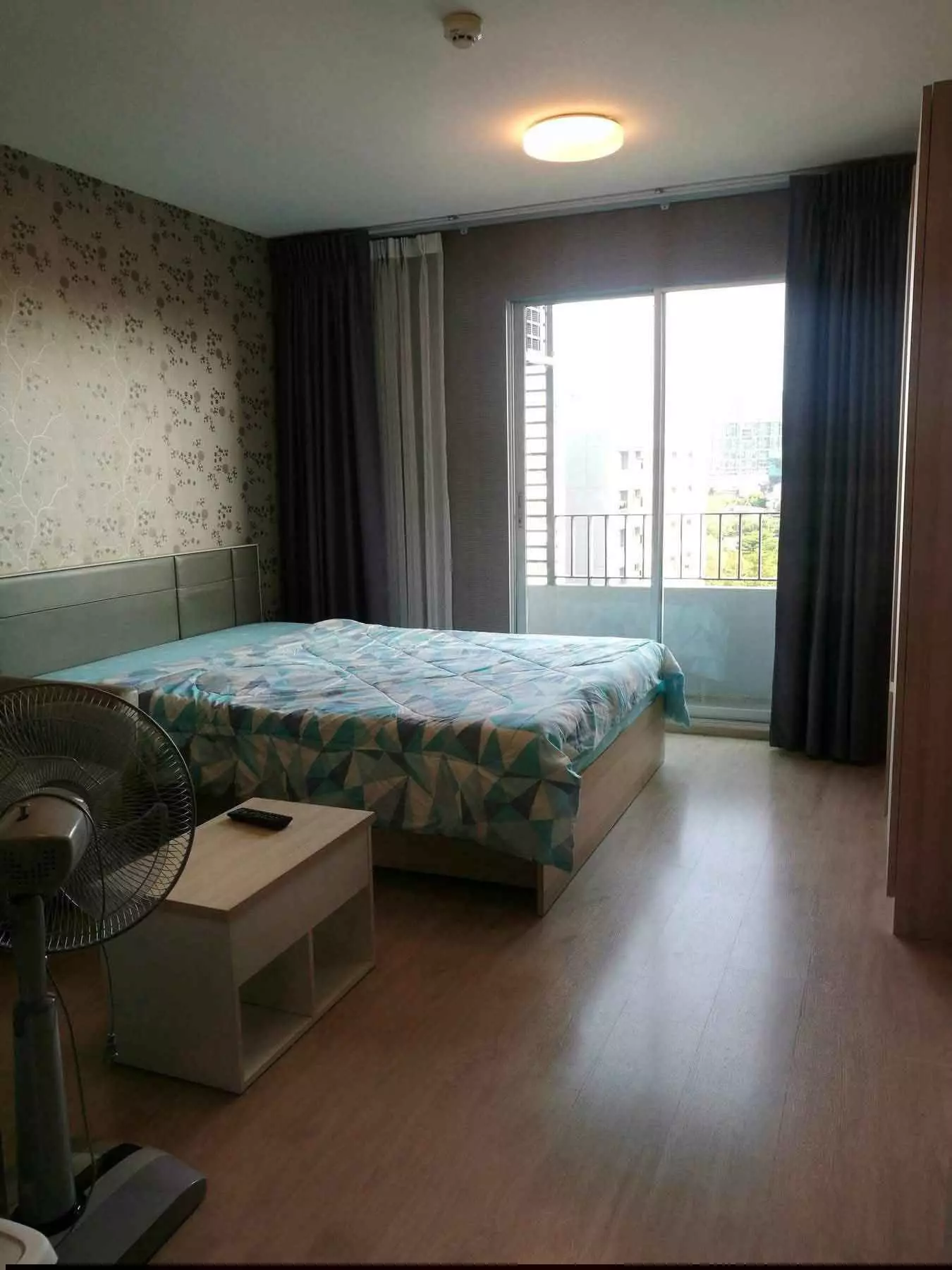 Bedroom in Elio Del Ray condo with wood floors, grey bed, and balcony doors