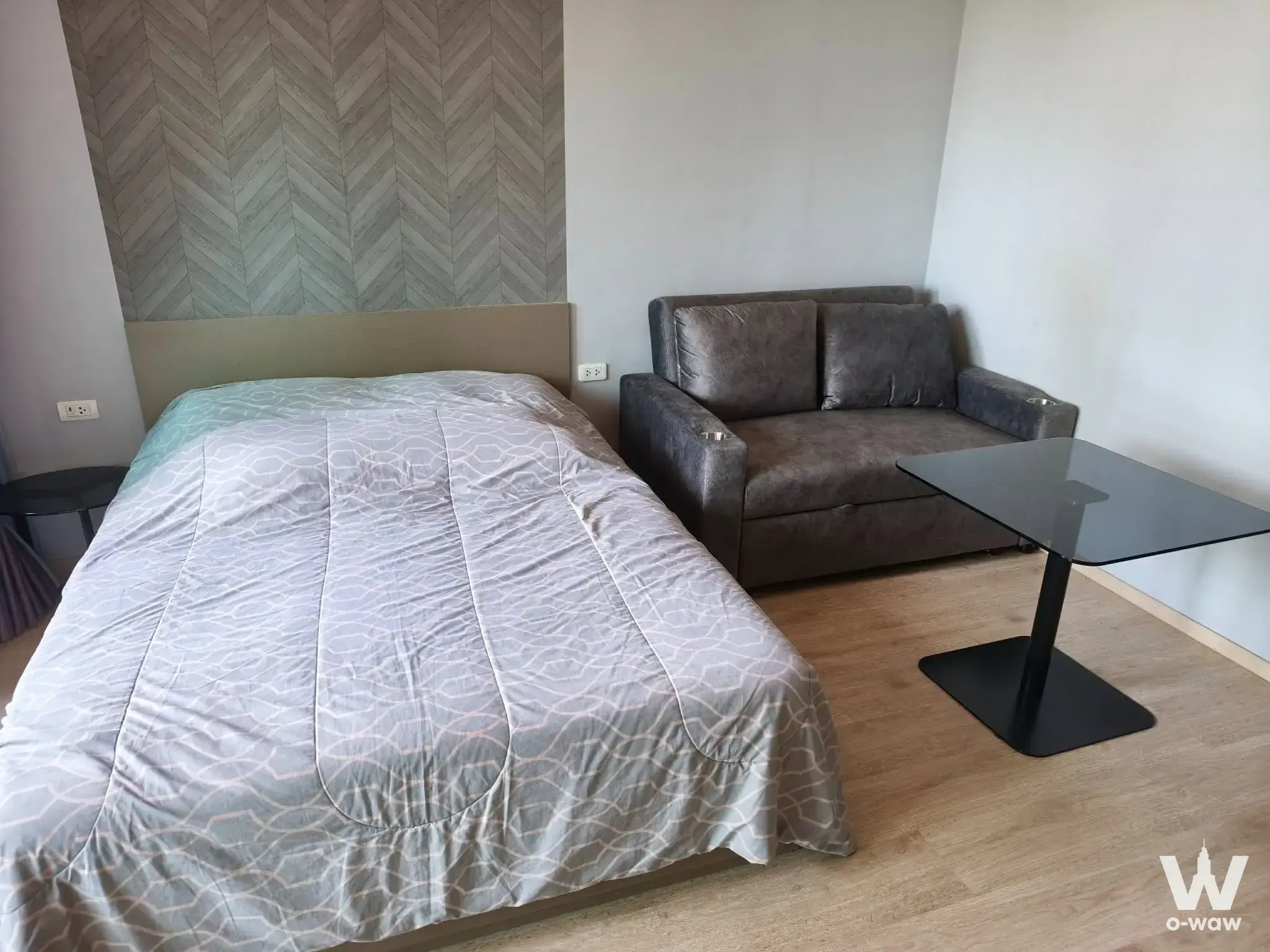 Modern 1-bed studio in Ideo Sathon with queen bed, herringbone accent wall and dark leather sofa