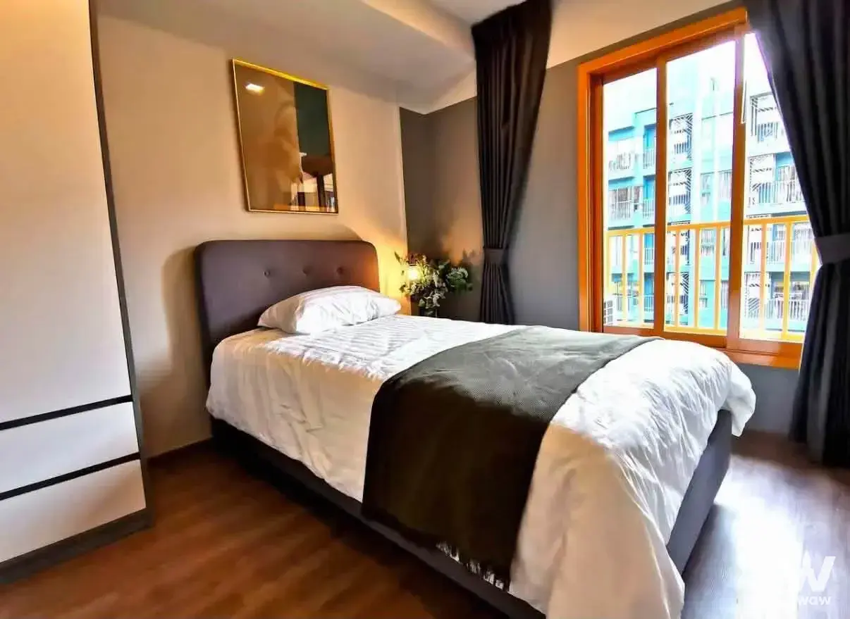Modern bedroom with dark grey feature wall, white wardrobe, and orange window frame overlooking city