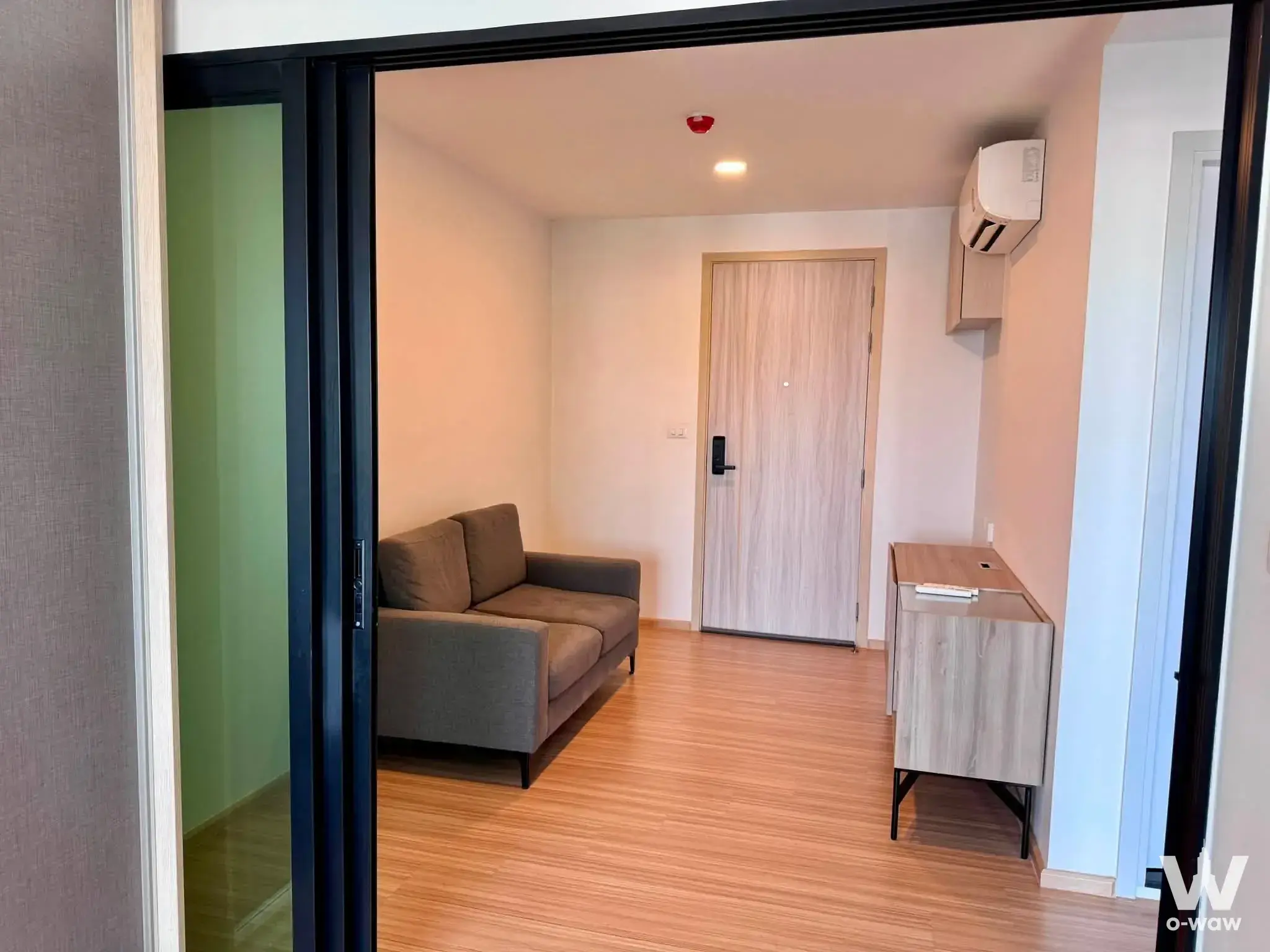 Chewathai Hallmark Ladprao 1-bed condo entryway with black folding glass doors and light wood laminate flooring