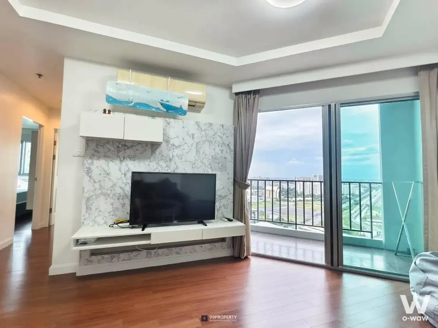 Bright living room in a 2-bed condo for rent at Belle Grand Rama 9 featuring wood floors and a balcony with city views