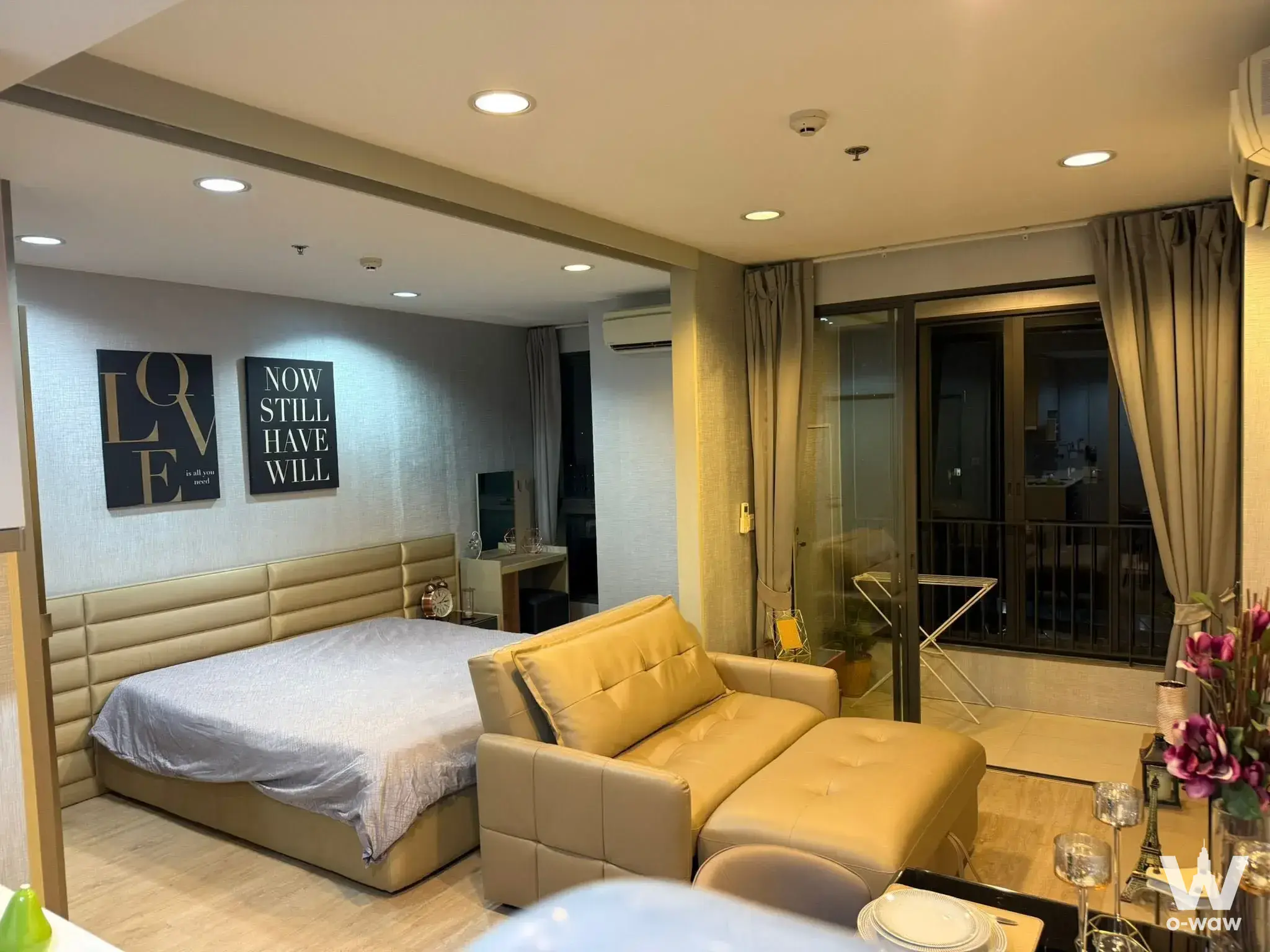 Studio bedroom in Ideo Q Ratchathewi with bed, chaise lounge, and balcony access through sliding glass doors