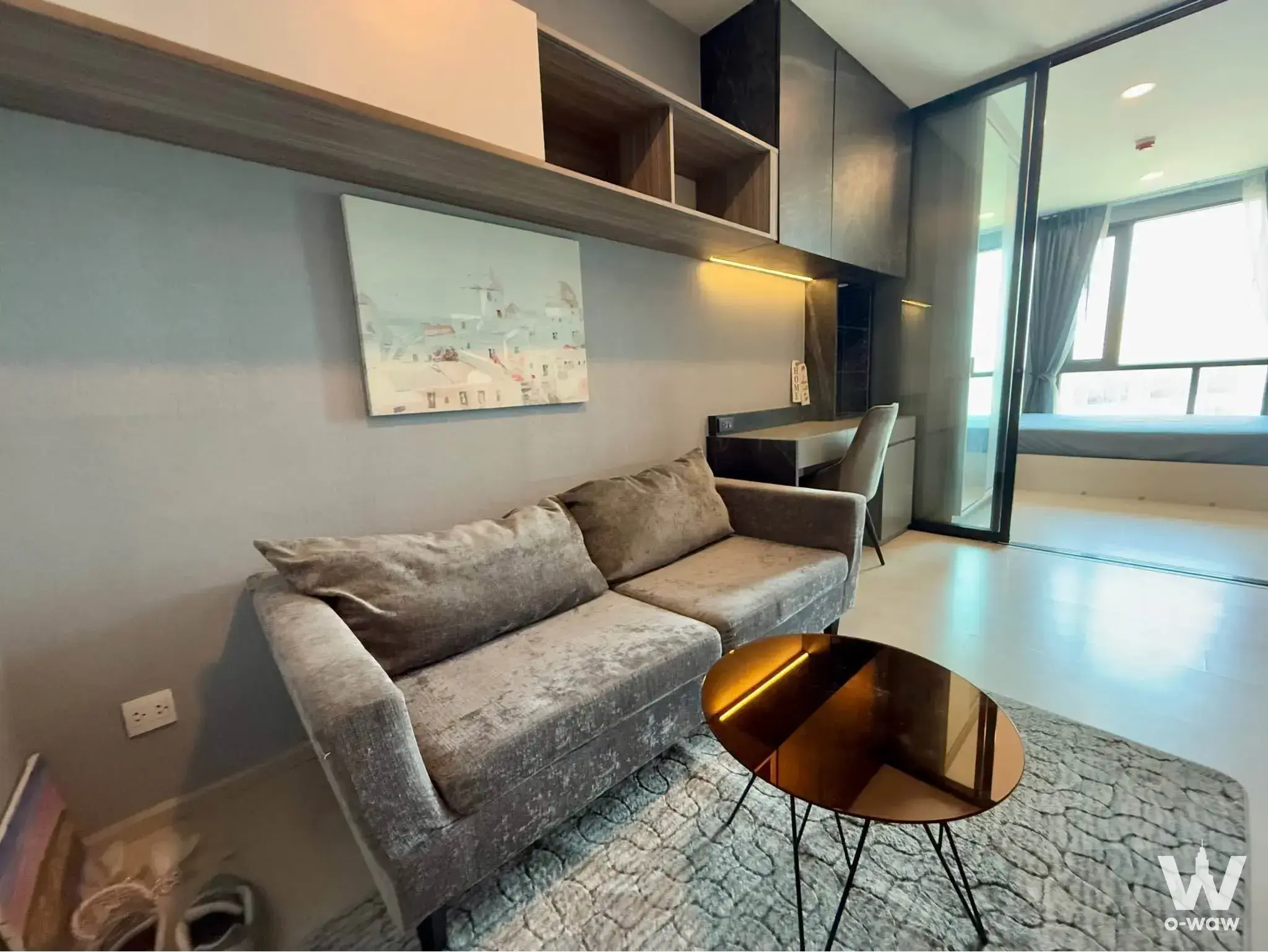 Studio living space at KnightsBridge Phaholyothin Interchange with grey velvet sofa and glass partition