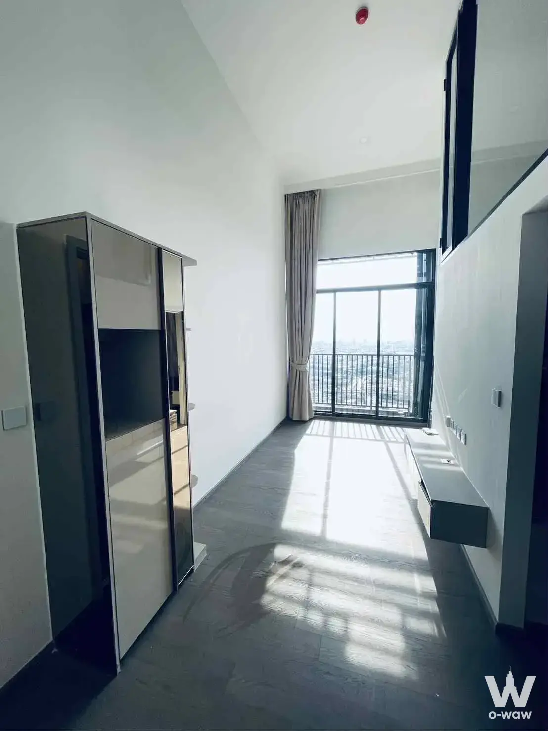 This narrow 1-bed condo living room in Park Origin Ratchathewi has a floor-to-ceiling glass door and city view