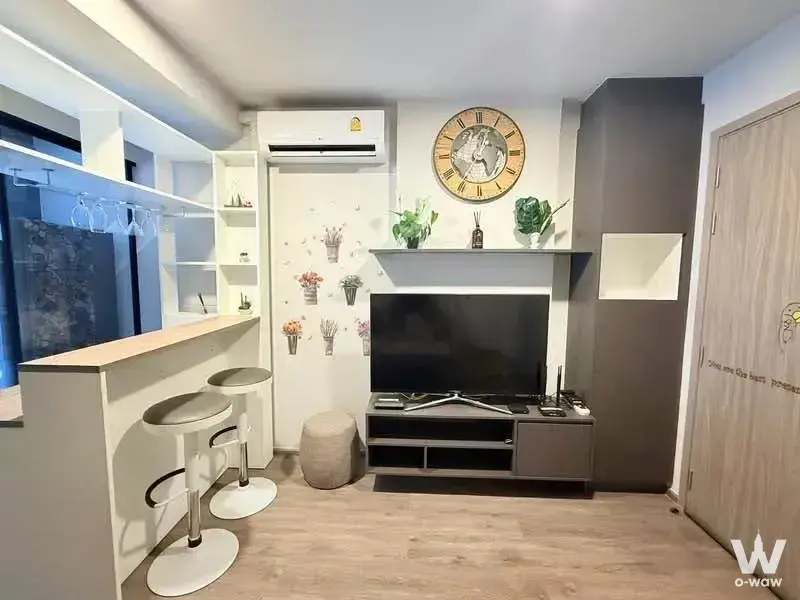 Monte Rama9 1-bed condo living room featuring grey console, gold clock, and bar