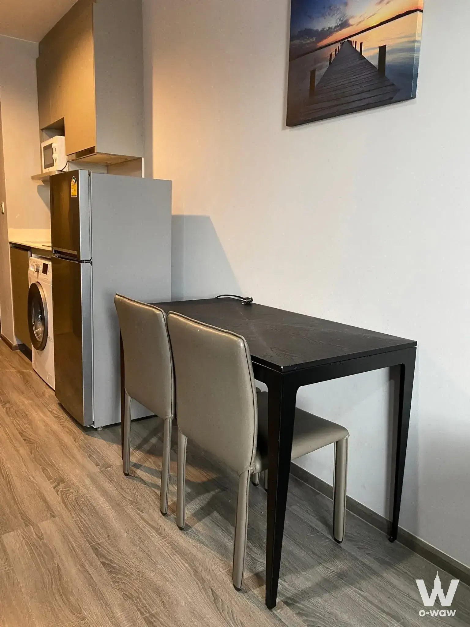 Compact dining nook in Ideo Mobi Rangnam with black table, beige chairs, and open-plan kitchenette