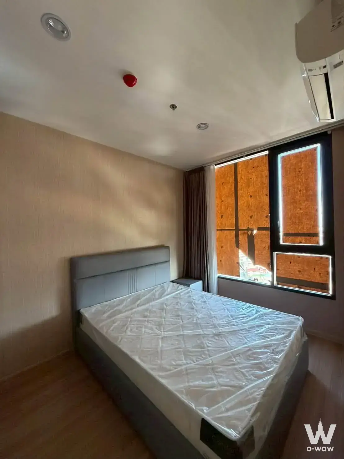 Bedroom in Skyrise Avenue Sukhumvit 64 with grey upholstered bed frame and large window with drapes