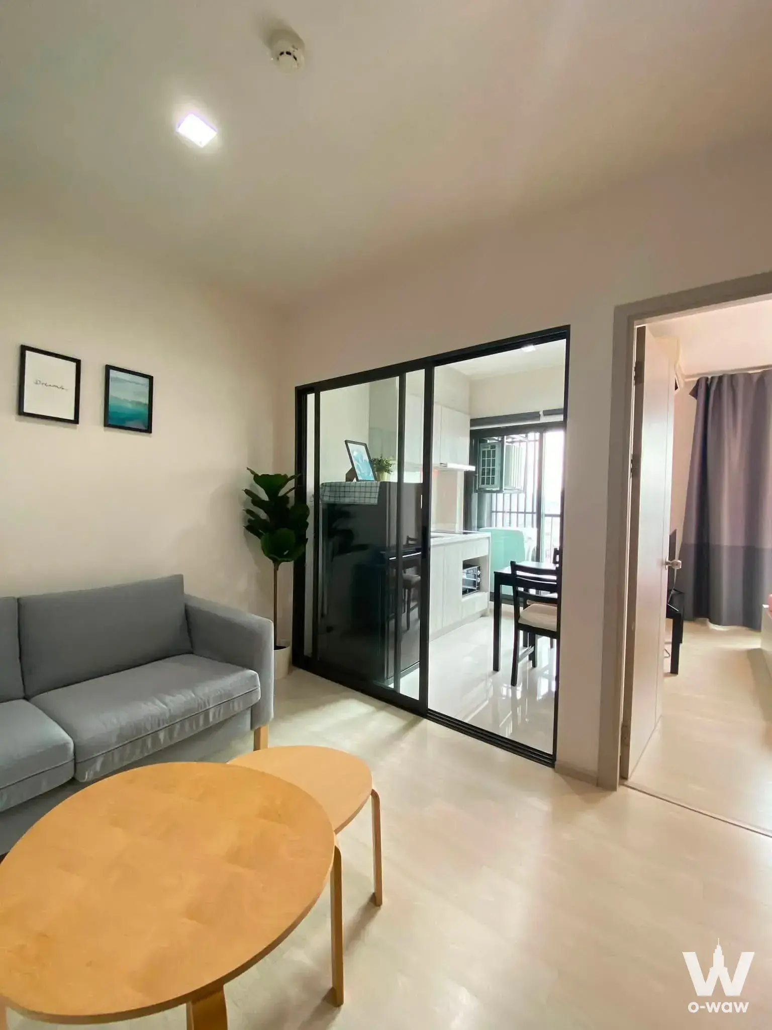 Bright living room in a Life Sukhumvit 48 rental featuring a grey sofa and glass partition