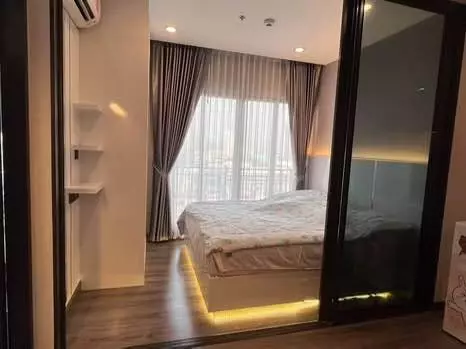 Bedroom with LED-lit platform bed and mirrored wardrobe in 1-bed condo for sale at Urbano Rajavithi