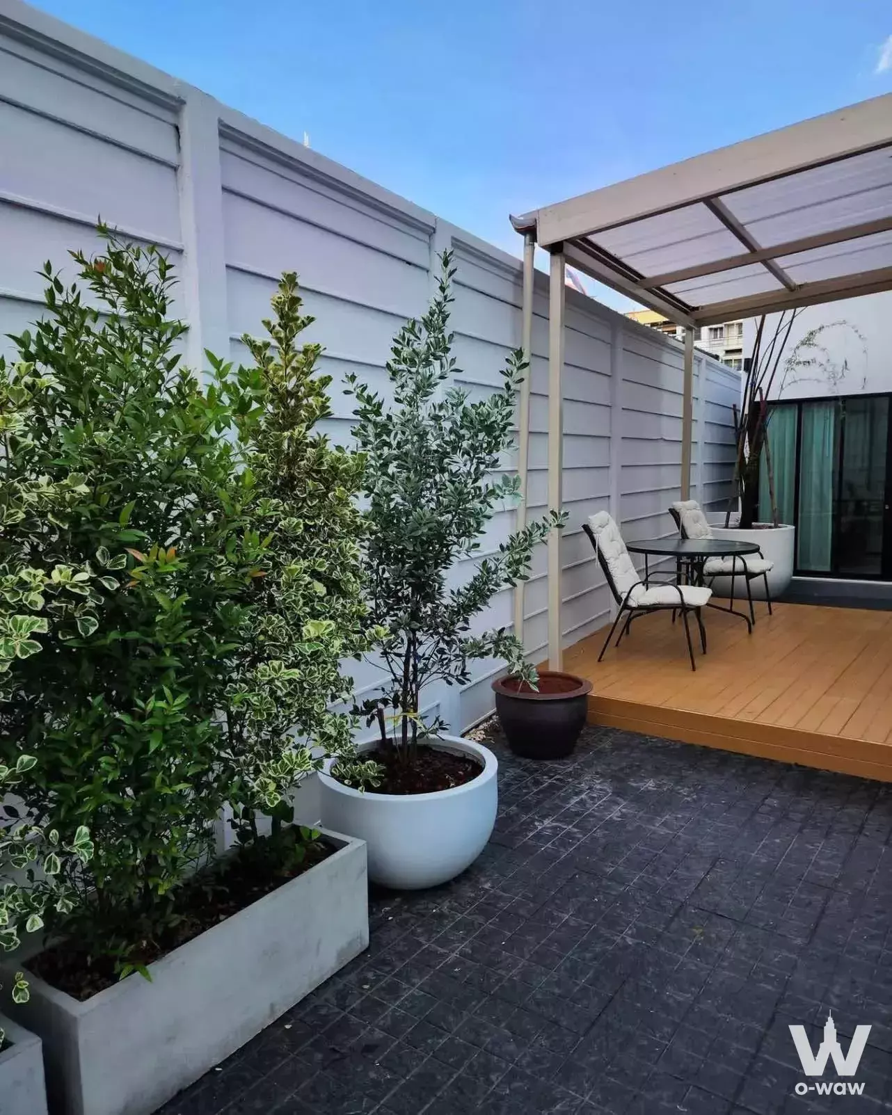 Outdoor terrace of 4-bed townhouse in Areeya Mandarina with wooden deck, pergola, dining set, and lush planters