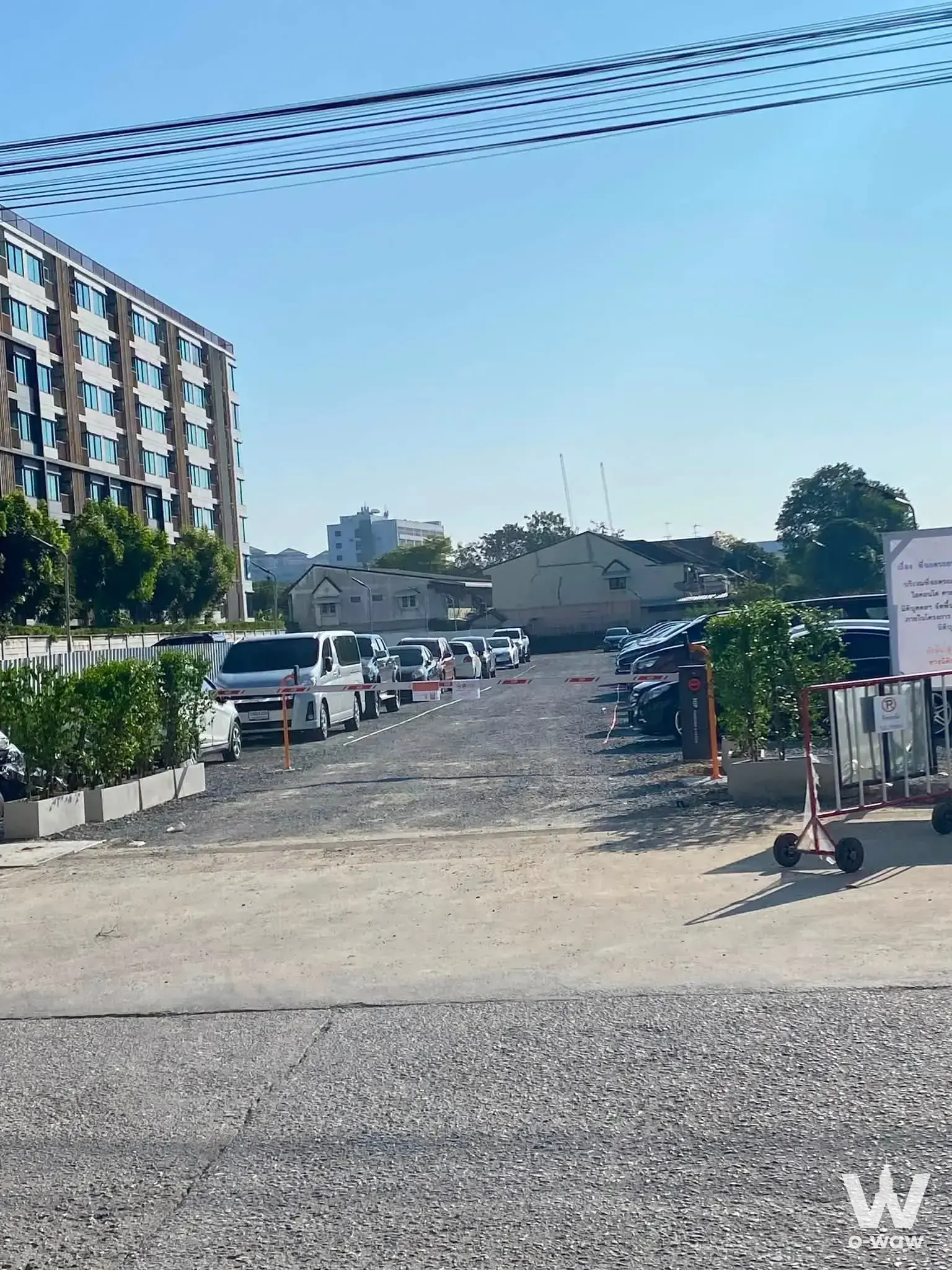 Exterior of i-Condo 1 Salaya condo for sale showing beige facade, parking lot with white van, and red barrier tape under