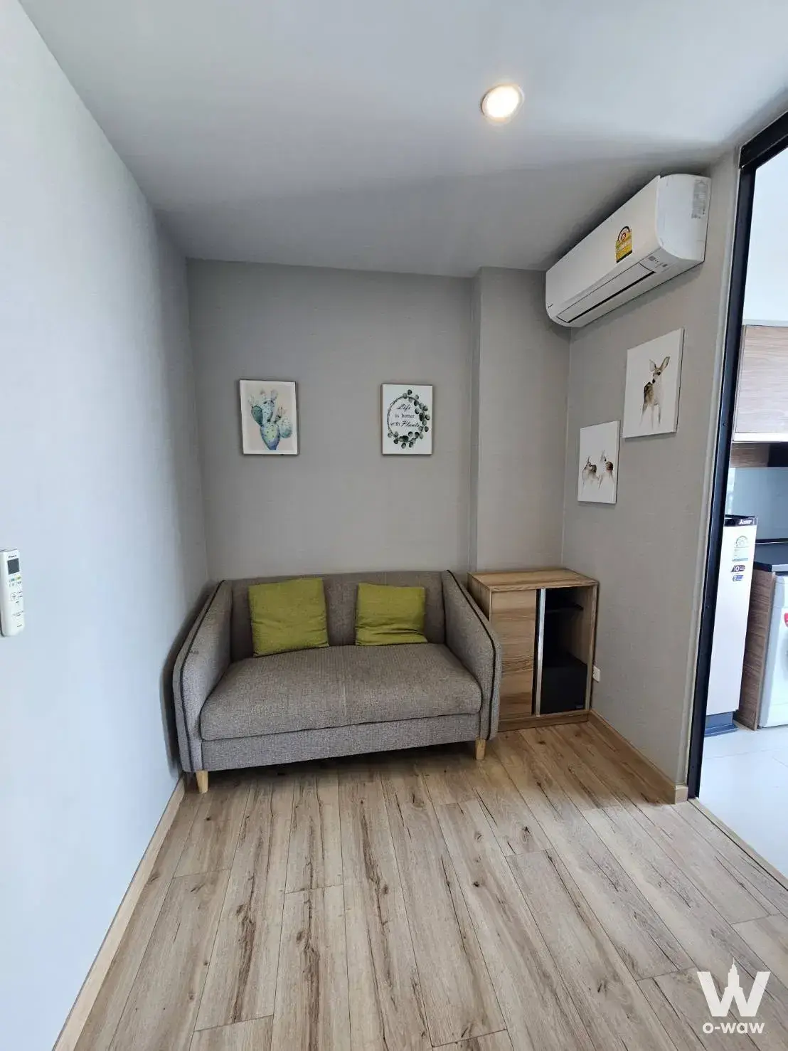 Modern living room in Brix Charan 64 with grey sofa, lime-green pillows, and framed art