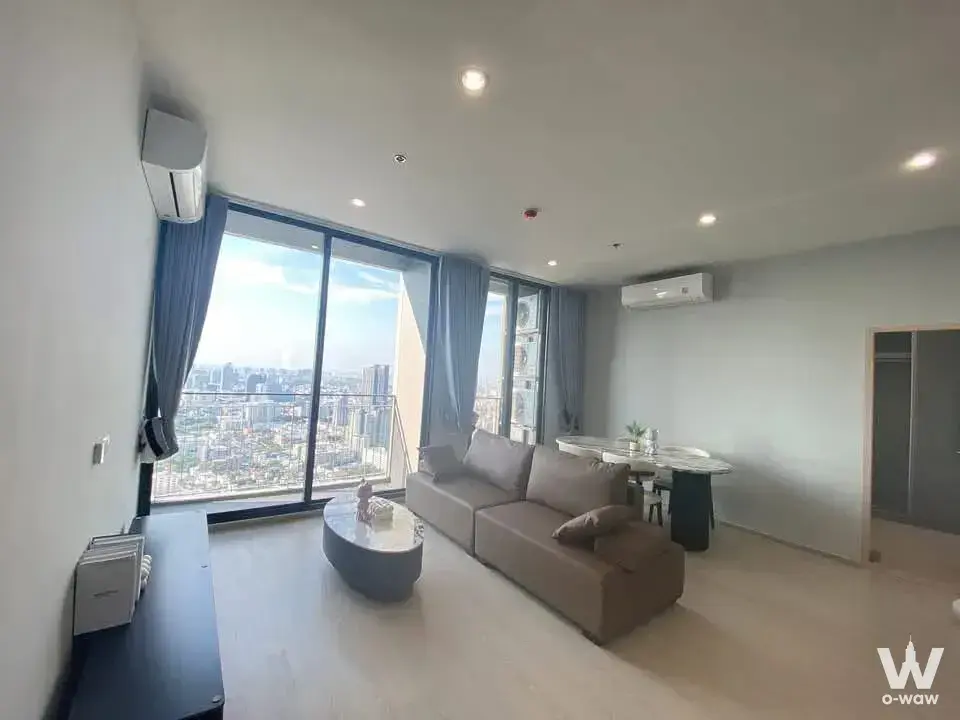 Living room in a 3-bed condo for rent in Skyrise Avenue Sukhumvit 64 with taupe sofa and skyline view