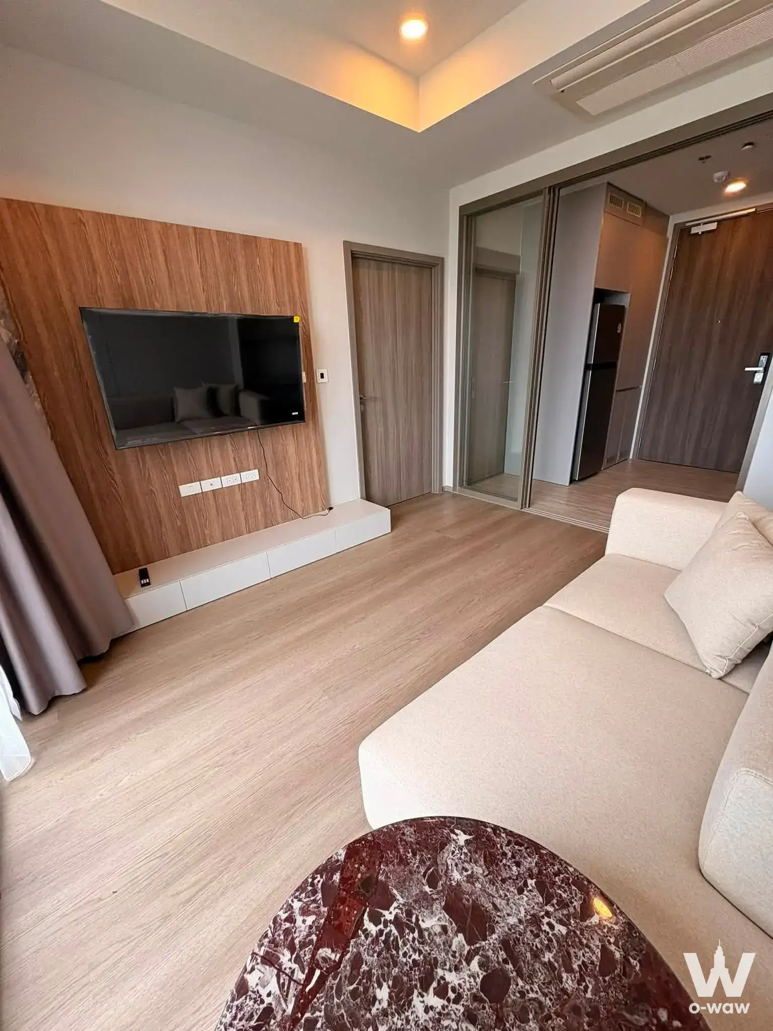 Living room in Whizdom The Forestias 1-bed condo with beige sofa and recessed wall-mounted TV