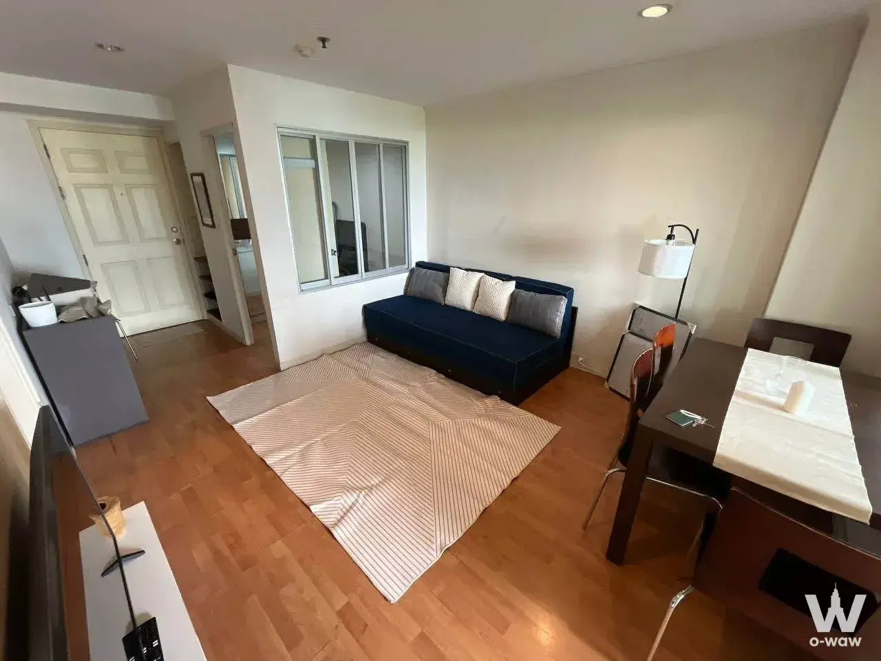 Living room in Lumpini Ville Sukhumvit 77-2 2-bed rental with navy sofa, dining table, and wood-look floors