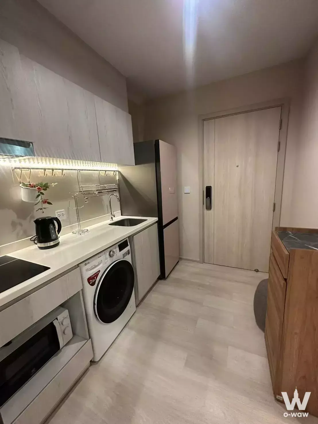 Modern kitchen in Life One Wireless with white cabinets, induction cooktop, and built-in washing machine
