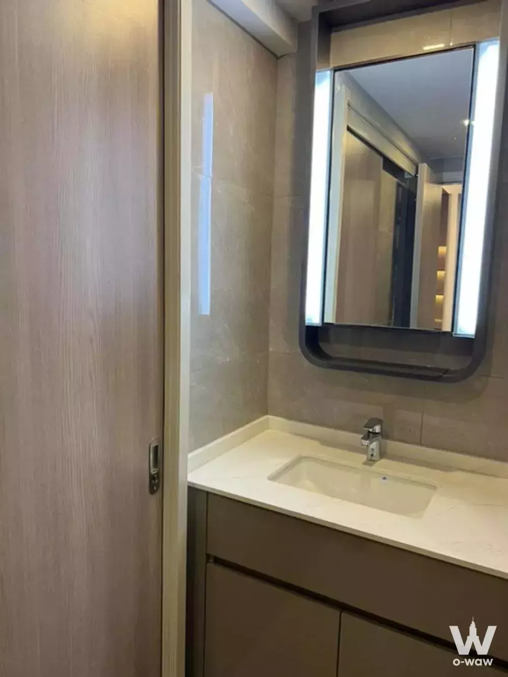 Modern bathroom vanity with beige marble-effect walls and taupe cabinet in One9Five Asoke 1-bed condo