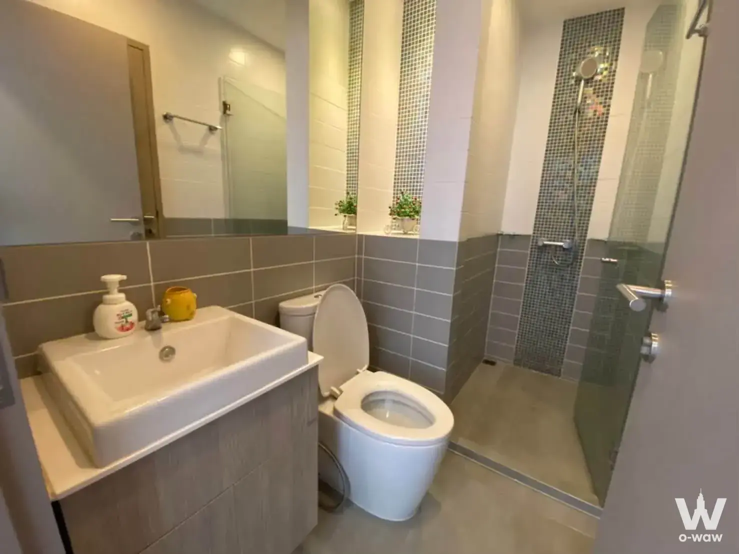 The bathroom in a 2-bed Ideo Mobi Sukhumvit 81 condo has a wood vanity, a mirror and a walk-in shower