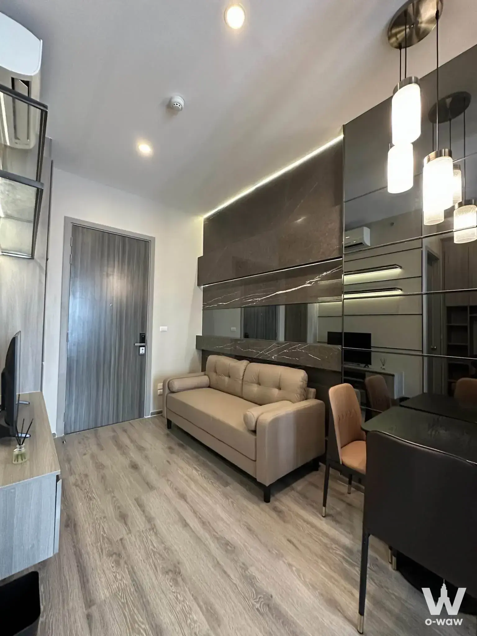 Open-plan living area in KnightsBridge Prime Onnut 1-bed for sale with grey marble wall and beige sofa