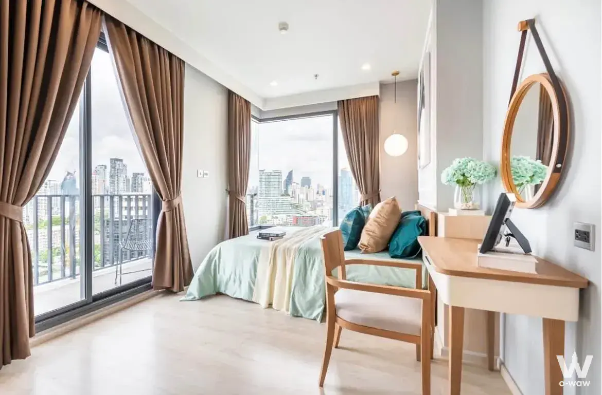 Queen bed in a modern 2-bed condo bedroom at M Thonglor 10 with floor-to-ceiling windows and city skyline view